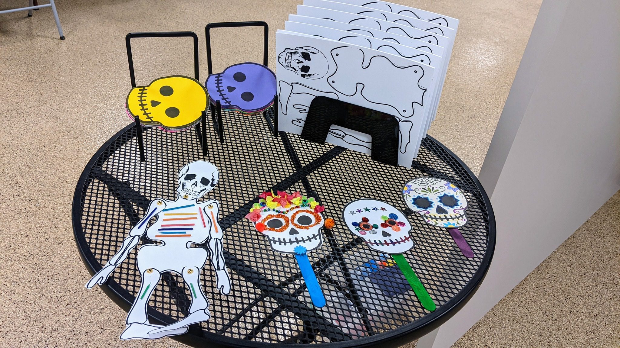 Collage of paper skeletons and skulls made with a variety of craft supplies.