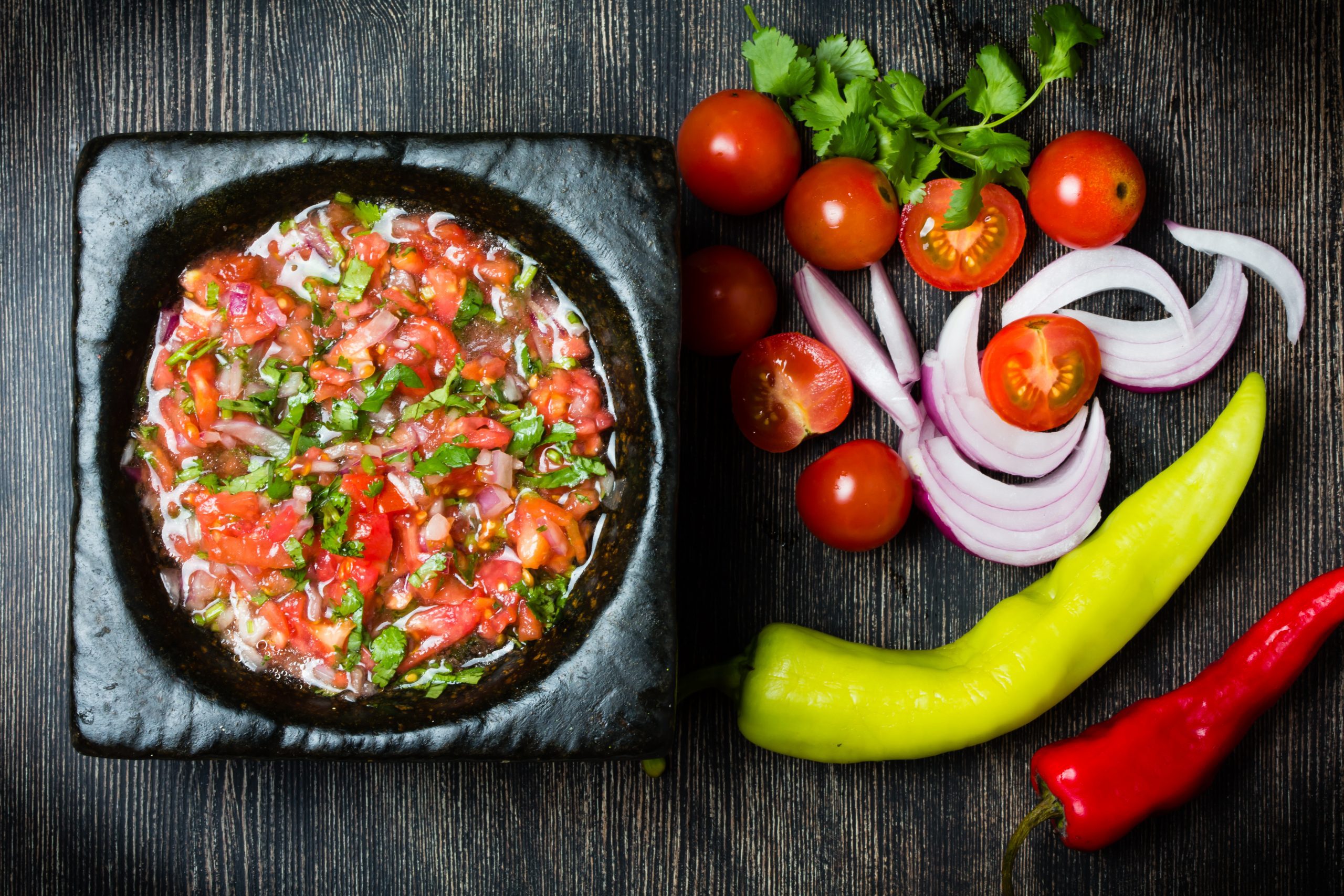 Tomato sauce salsa and ingredients dark stone background.