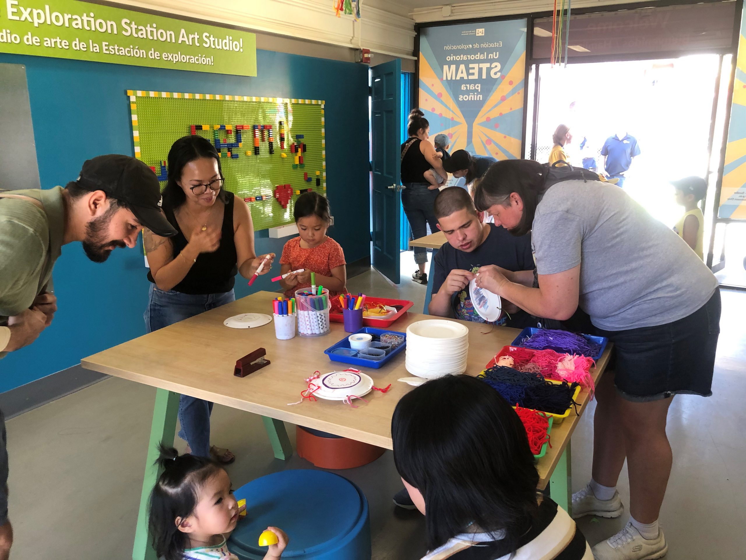 Several people sitting at a table, enjoying a conversation with a child who is playfully engaged with them.