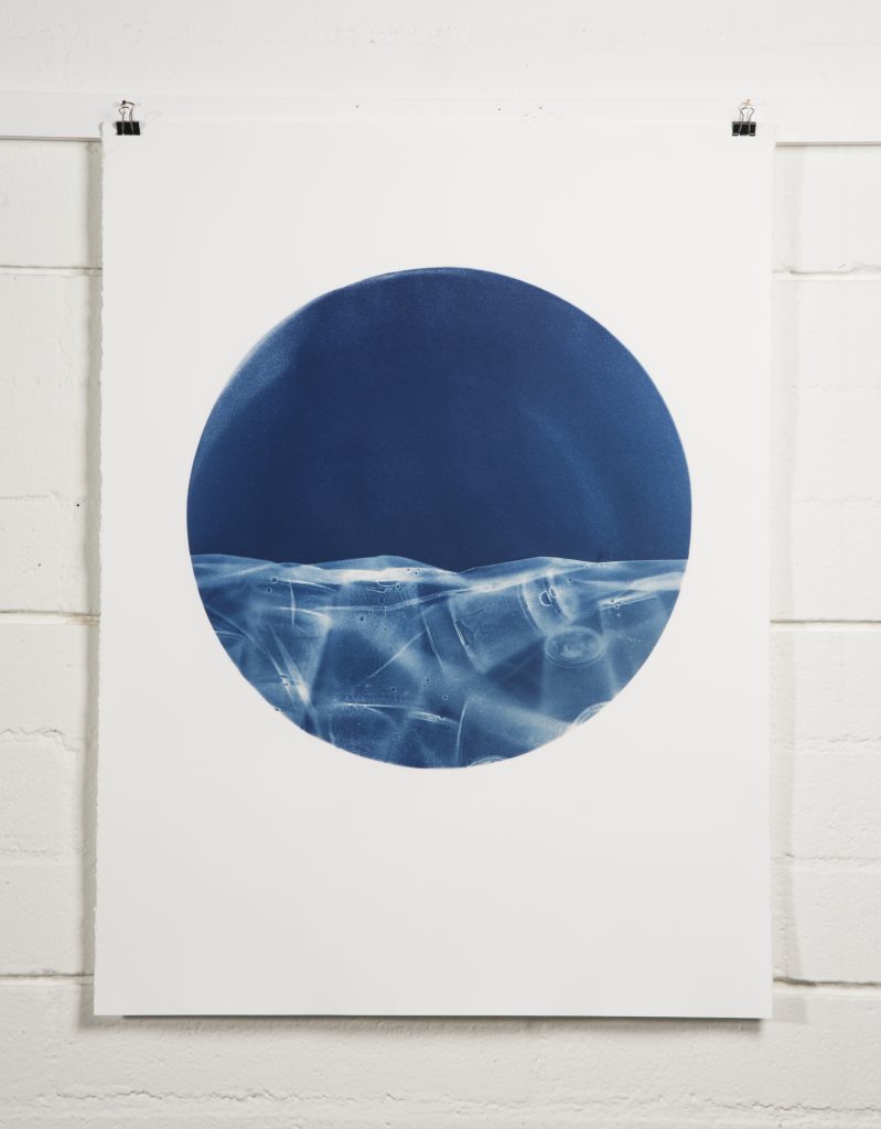 Minimal artwork of a deep blue circle with a lighter, icy-textured band across its lower half, resembling a horizon or frozen landscape.