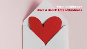 A red paper heart partially tucked inside a white envelope, set against a soft pink background. Text reads: “Second Saturday – Have A Heart: Acts of Kindness.”