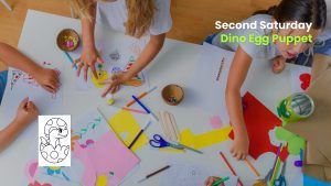 Children drawing and crafting at a table filled with paper, markers, and supplies during a “Second Saturday” puppet activity.